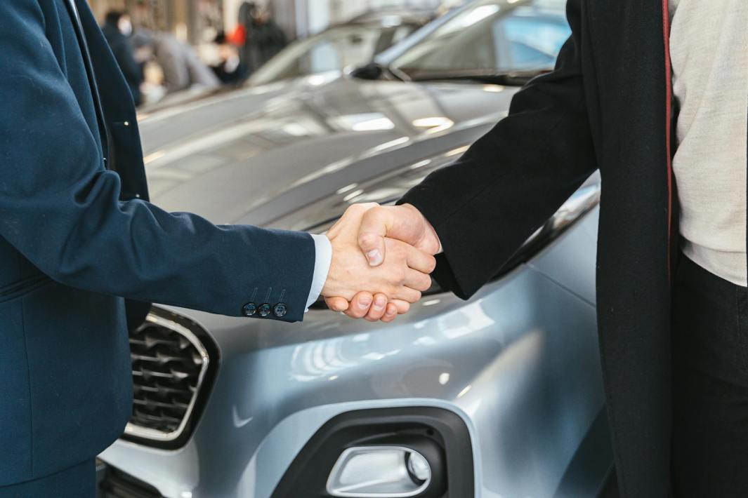 shaking hands over car